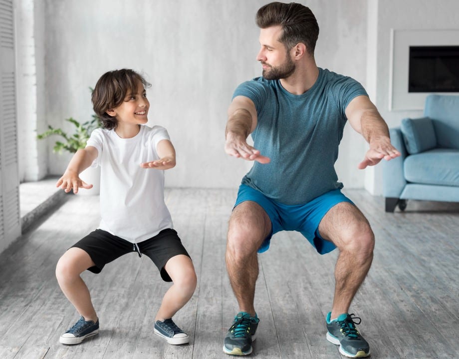 Vader en zoon doen samen squats thuis – kracht en balans voor drukke vaders