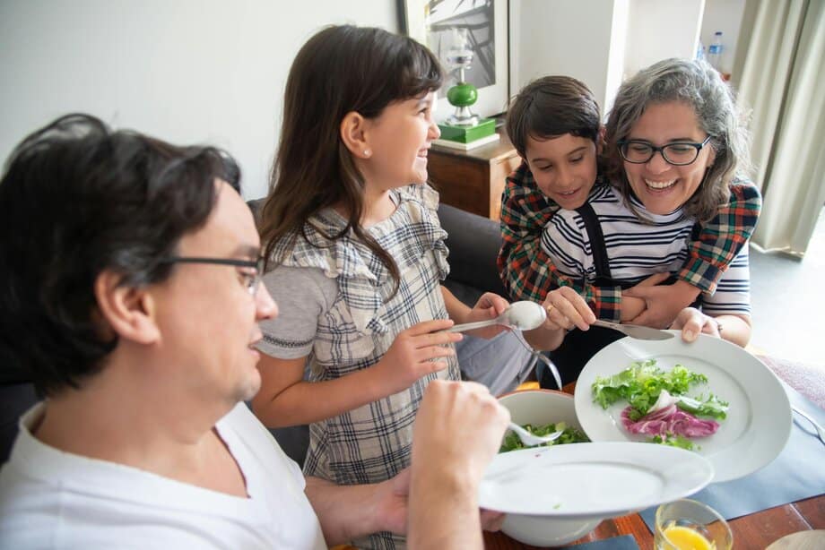 ader, vrouw, dochter en zoon eten samen aan tafel met sla op het bord