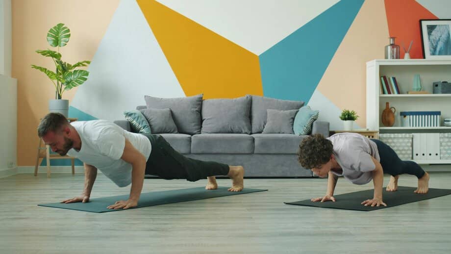 Vader en zoon doen push-ups op sportmatje in woonkamer