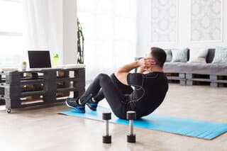 Drukke vader traint thuis met dumbbell op kleine ruimte