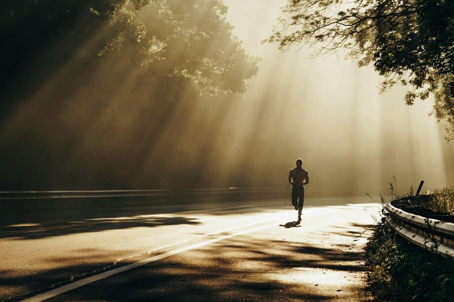 Man loopt op hoge intensiteit op een verlaten weg tijdens een interval hardlooptraining