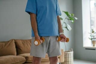 Vader van boven de 35 traint thuis met dumbbells voor spierbehoud